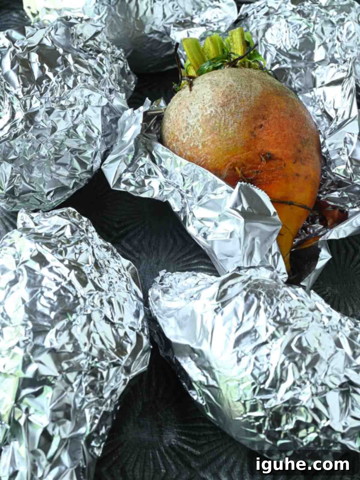 Aromatic Golden Beet Salad with Tarragon Vinaigrette 6 Beets wrapped in foil, with one partially unwrapped to show the golden color, on a baking sheet.
