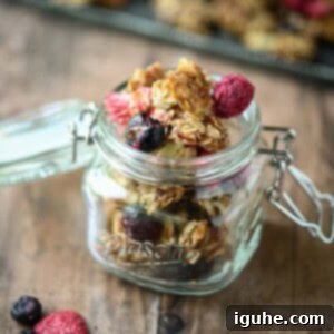 Berry Harvest Granola 10 Close-up of berry granola in a clear mason jar on a wood surface.