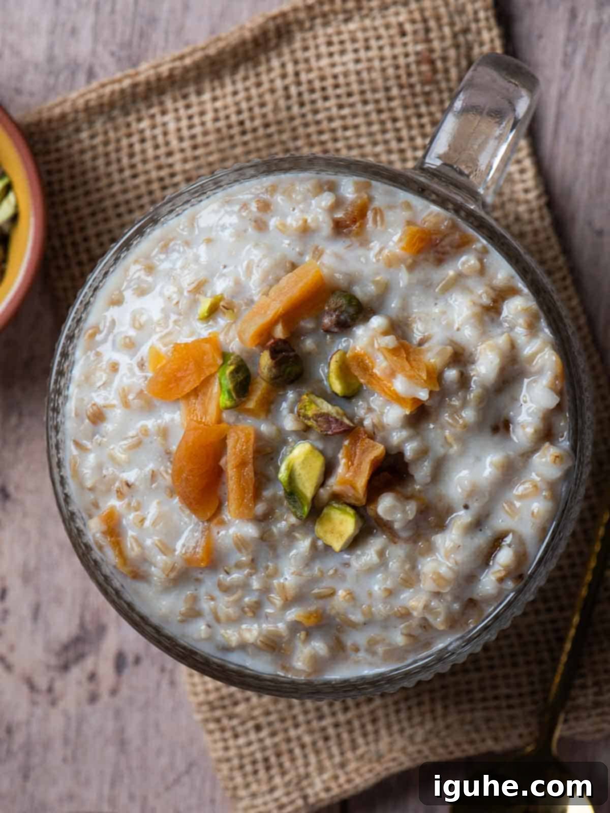 Velvet Apricot Porridge 8 Overhead of apricot oatmeal in a bowl on a piece of burlap.