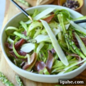 Delicate Asparagus & Prosciutto Salad 9 Angled view of asparagus salad in a bowl with cheese and prosciutto.