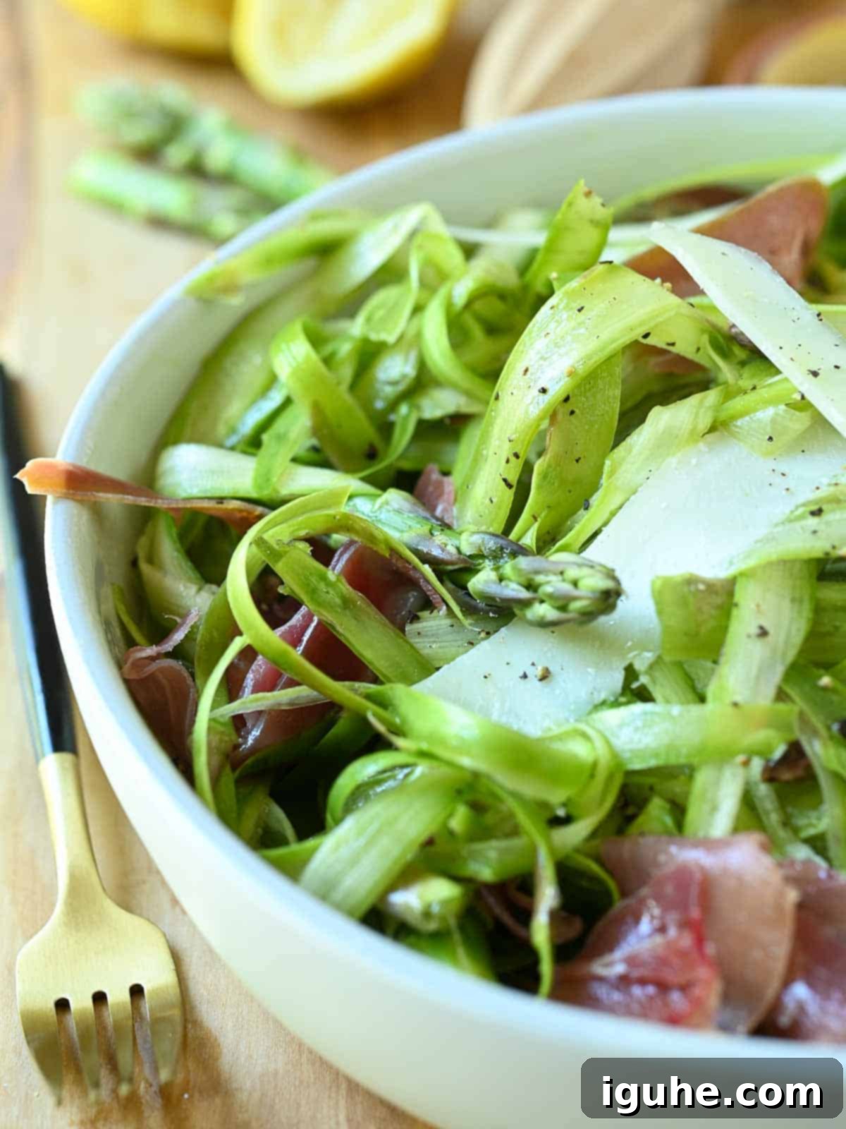 Delicate Asparagus & Prosciutto Salad 8 Close-up of shaved asparagus in a white bowl.