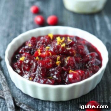 Luscious Vanilla Cranberry Compote 10 Cranberry compote in a white ramekin with cranberries and vanilla beans beside it.