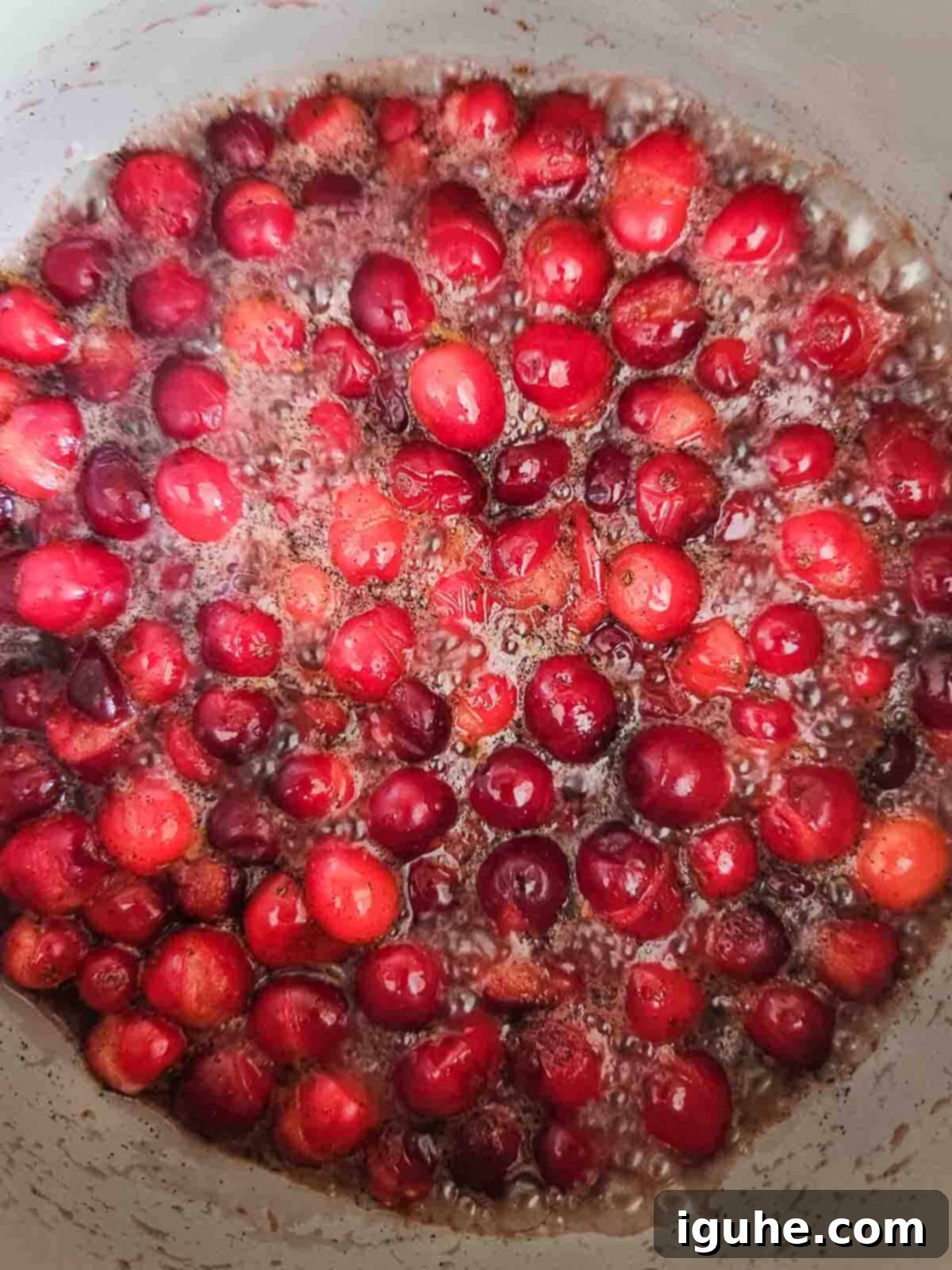 Luscious Vanilla Cranberry Compote 6 Cranberries bursting and simmering in a pot, thickening into compote.