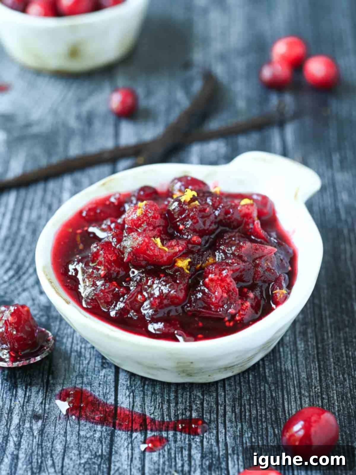 Luscious Vanilla Cranberry Compote 8 Small white bowl of cranberry compote on a grey surface, ready for serving.