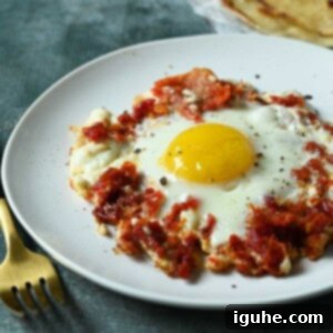 Sun-Kissed Feta and Tomato Fried Eggs 10 Close-up of a sun-dried tomato and feta fried egg, showing the crispy cheese edges and a vibrant, perfectly cooked yolk.