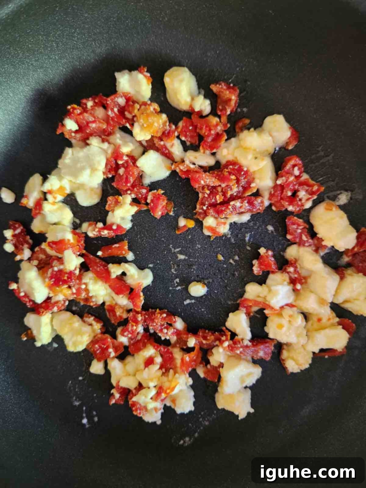 Sun-Kissed Feta and Tomato Fried Eggs 4 Finely crumbled feta cheese and diced sun-dried tomatoes with fresh herbs beginning to crisp in a hot skillet, carefully arranged into a neat circle with a space in the center.