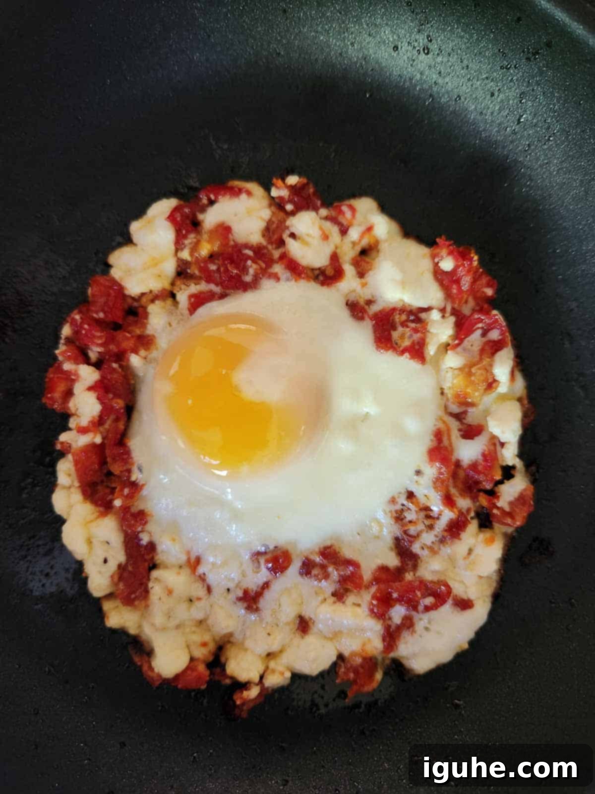 Sun-Kissed Feta and Tomato Fried Eggs 7 A perfectly cooked sun-dried tomato and feta fried egg, showcasing a golden crispy crust and a set egg white, still resting in the non-stick skillet.