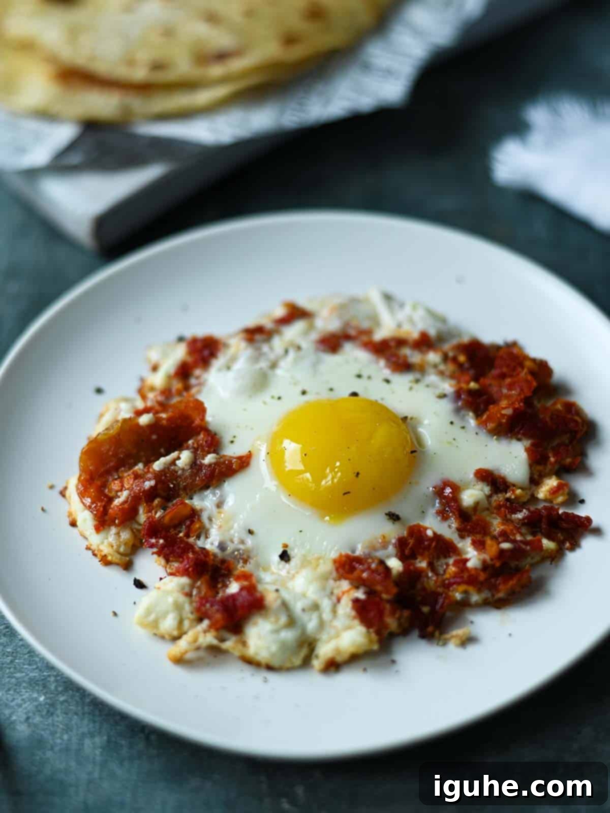 Sun-Kissed Feta and Tomato Fried Eggs 8 A beautifully plated sun-dried tomato and feta fried egg, golden and crispy, adorned with fresh herbs, ready to be enjoyed on a clean white plate.