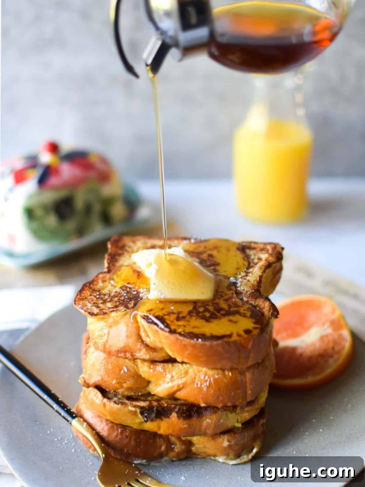 Aromatic Orange Cardamom French Toast 2 Straight on view of orange and cardamom french toast with maple syrup being poured from above on a grey background
