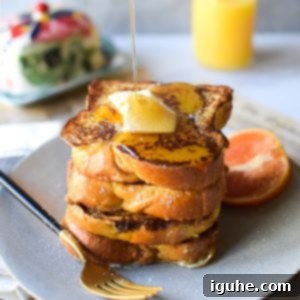 Aromatic Orange Cardamom French Toast 3 Straight on view of orange and cardamom french toast with maple syrup being poured from above on a grey background