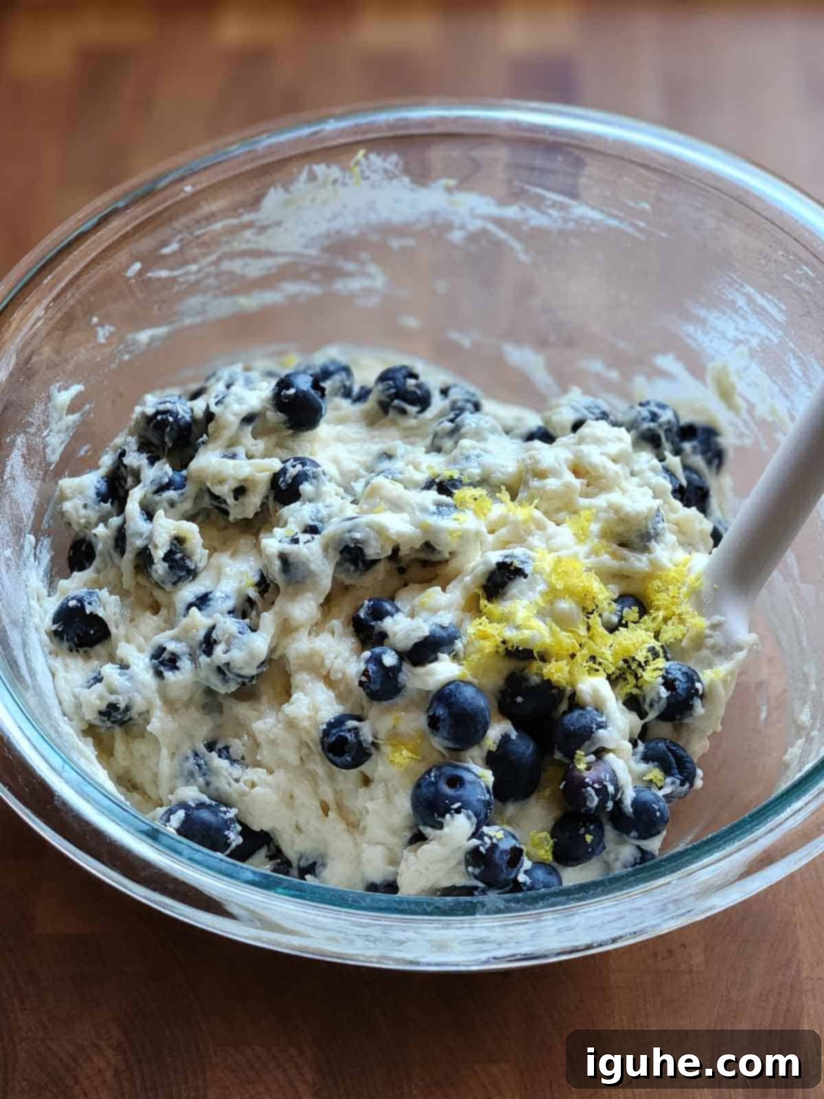 Blueberry Burst Skillet Pancake 7 Blueberry pancake batter in a clear bowl with a spatula.