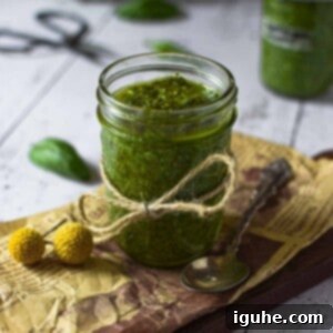 Golden Roasted Garlic Pesto 10 Roasted garlic pesto sauce in a clear jar on a wooden surface.