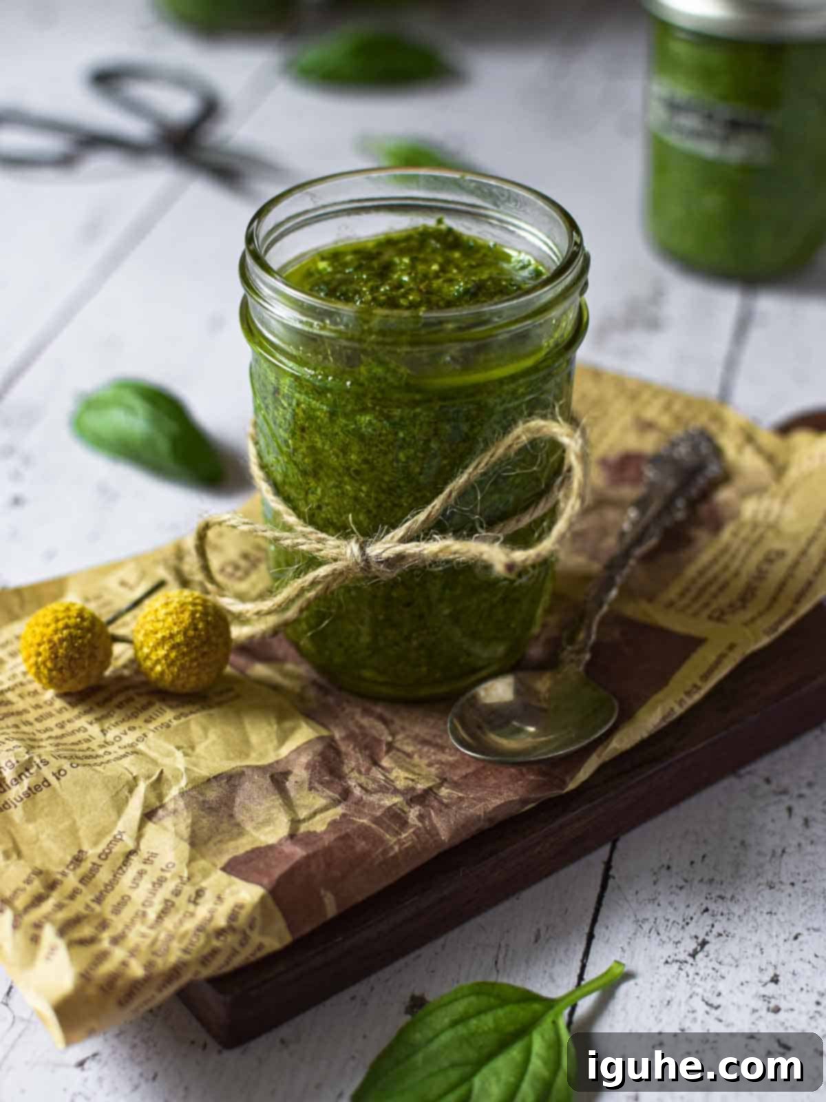 Golden Roasted Garlic Pesto 8 Angled view of pesto sauce in a small clear jar on a wooden surface.