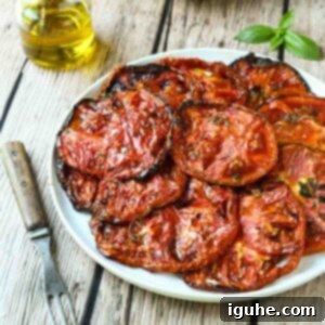 Sweet & Savory Slow Roasted Beefsteak Tomatoes 8 Roasted Beefsteak tomato slices on a white plate with a fork to the left.