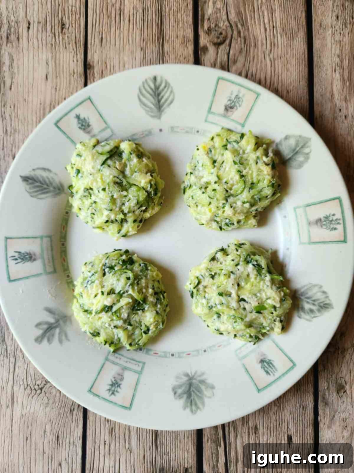 Crispy Zucchini Parmesan Fritters 5 Four uncooked zucchini patties neatly arranged on a white plate, ready for frying.