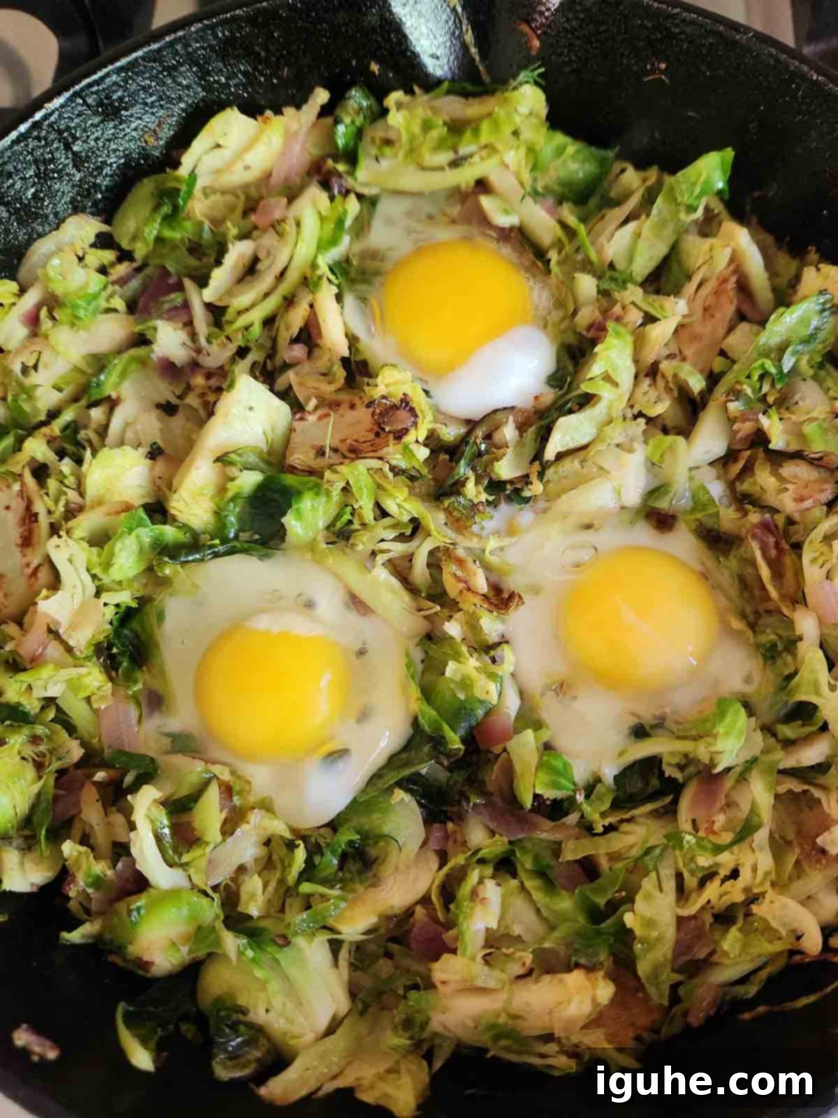 Crispy Sprout Skillet 9 Brussel sprouts in a black skillet with 3 eggs in it.