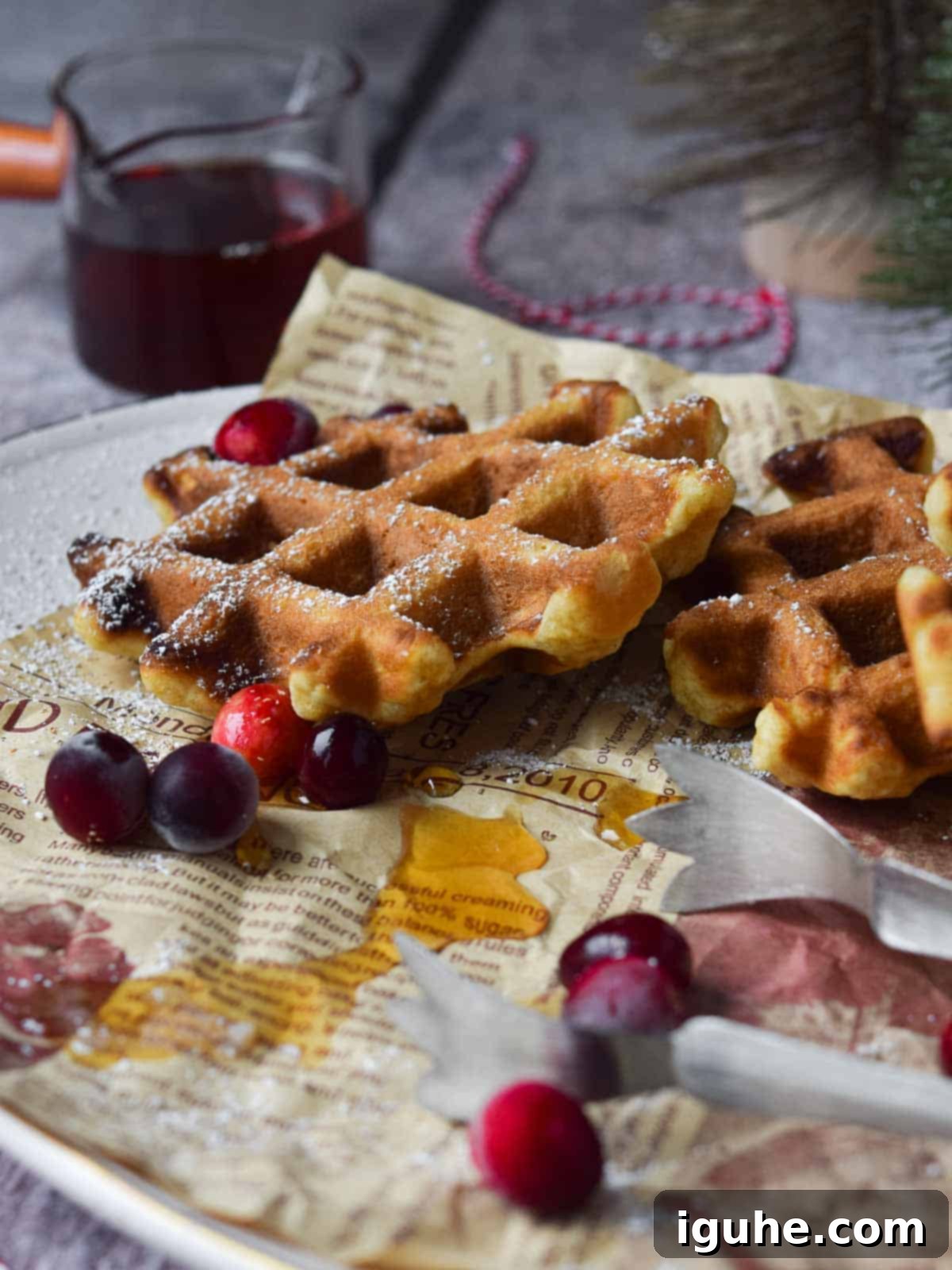 Festive Spiced Eggnog Waffles 11 A beautifully arranged platter of golden eggnog waffles, complete with serving tongs and a small pitcher of maple syrup, inviting guests to serve themselves.