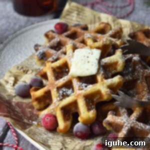 Festive Spiced Eggnog Waffles 12 Close-up of eggnog waffles on a platter with cranberries around it.