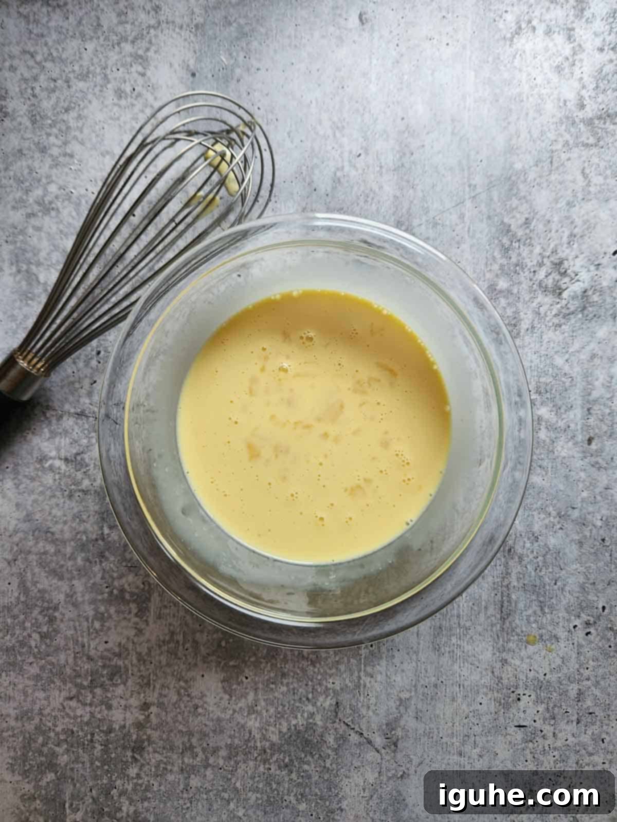 Holiday Eggnog Waffles 5 Wet ingredients for eggnog waffles in a separate bowl, including egg, sugar, and eggnog.
