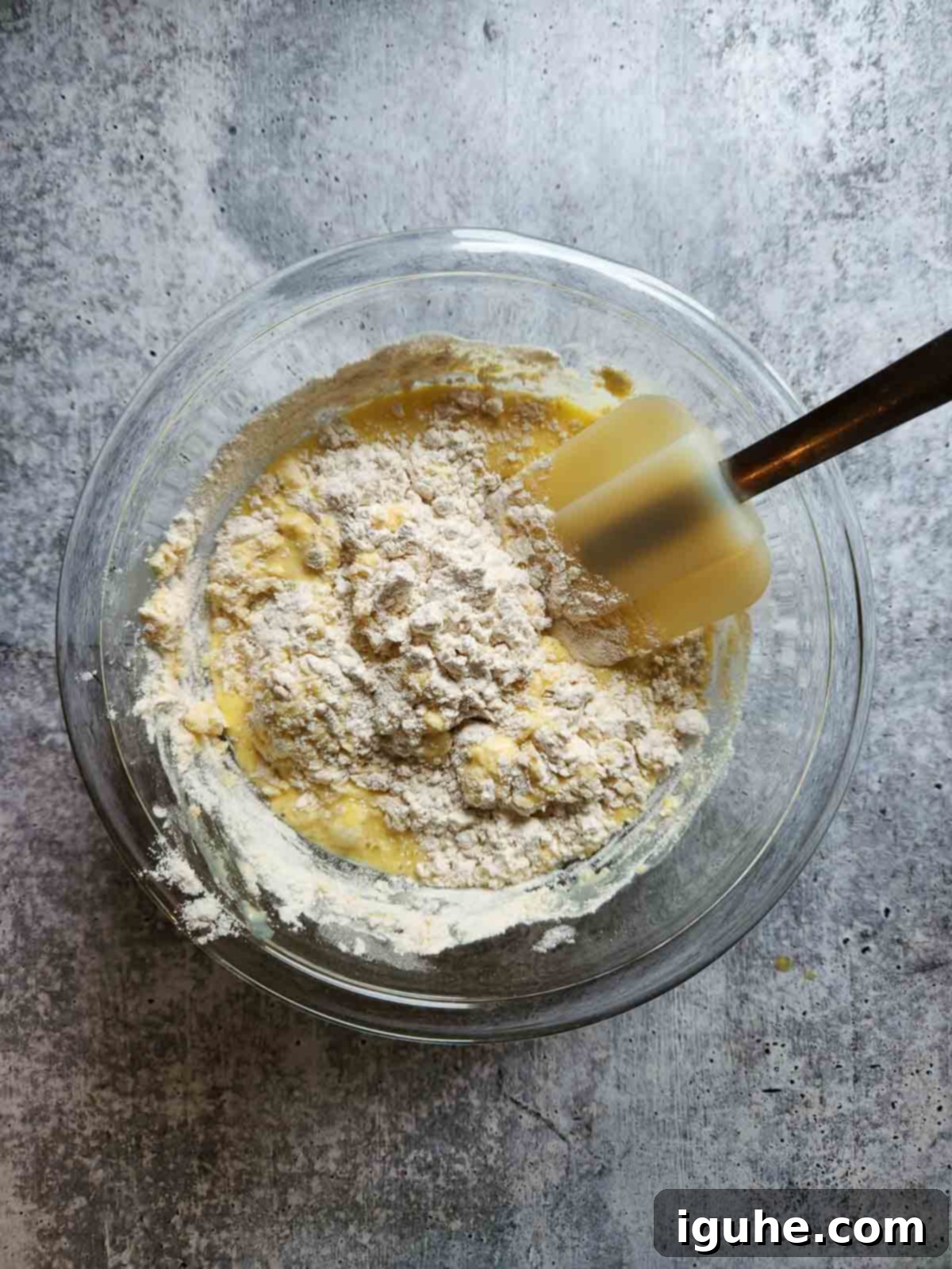 Festive Spiced Eggnog Waffles 6 The process of gently mixing wet ingredients into dry ingredients to form eggnog waffle batter, showing a bowl with flour mixture and eggnog mixture being combined.