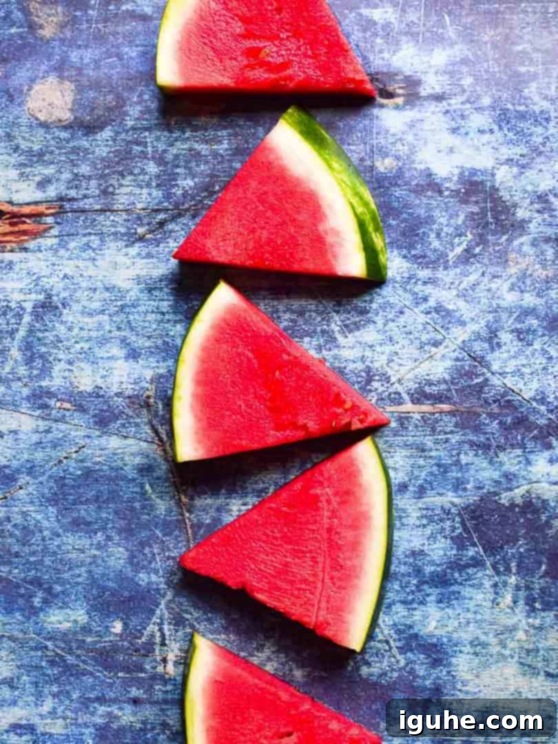 Pure Watermelon Refreshment 3 Overhead shot of vibrant red watermelon triangles on a blue cutting surface.