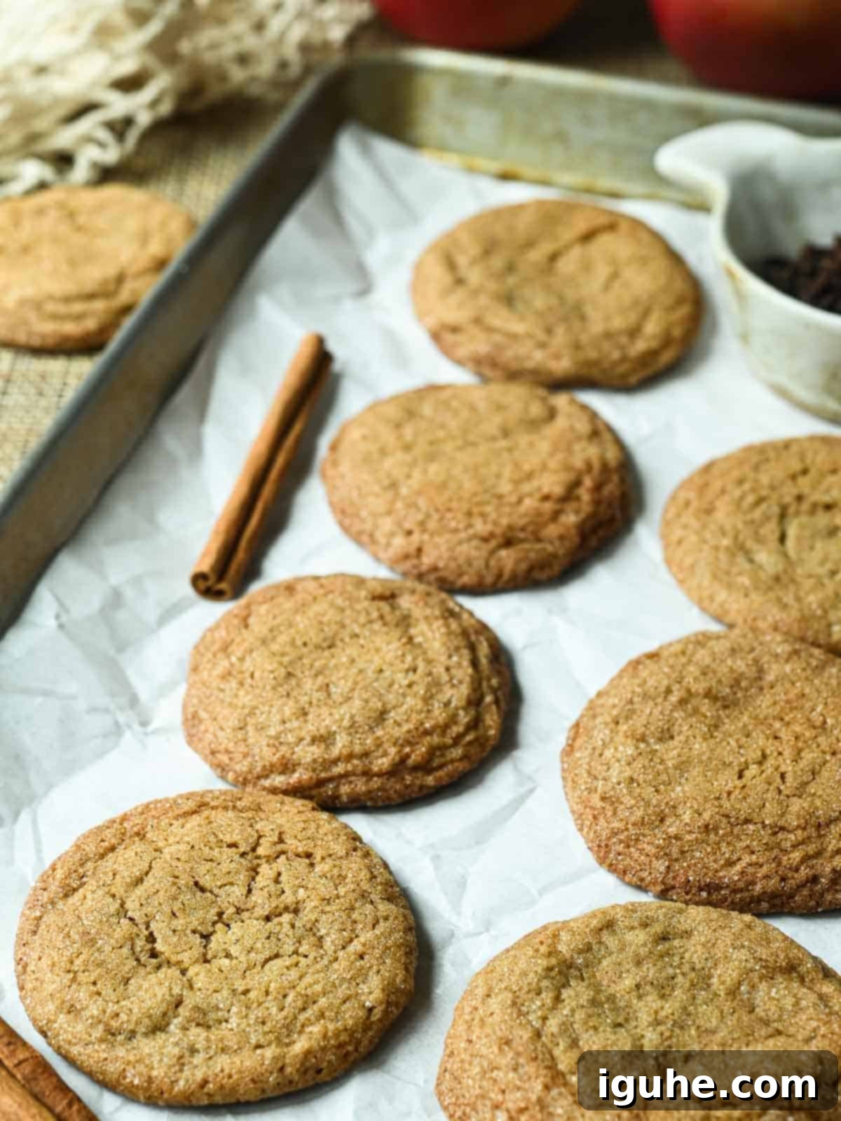 Autumn Apple Cider Cookies 6 Apple cider cookies freshly baked and cooling on a baking tray lined with parchment paper, showcasing their golden color and crackled tops.