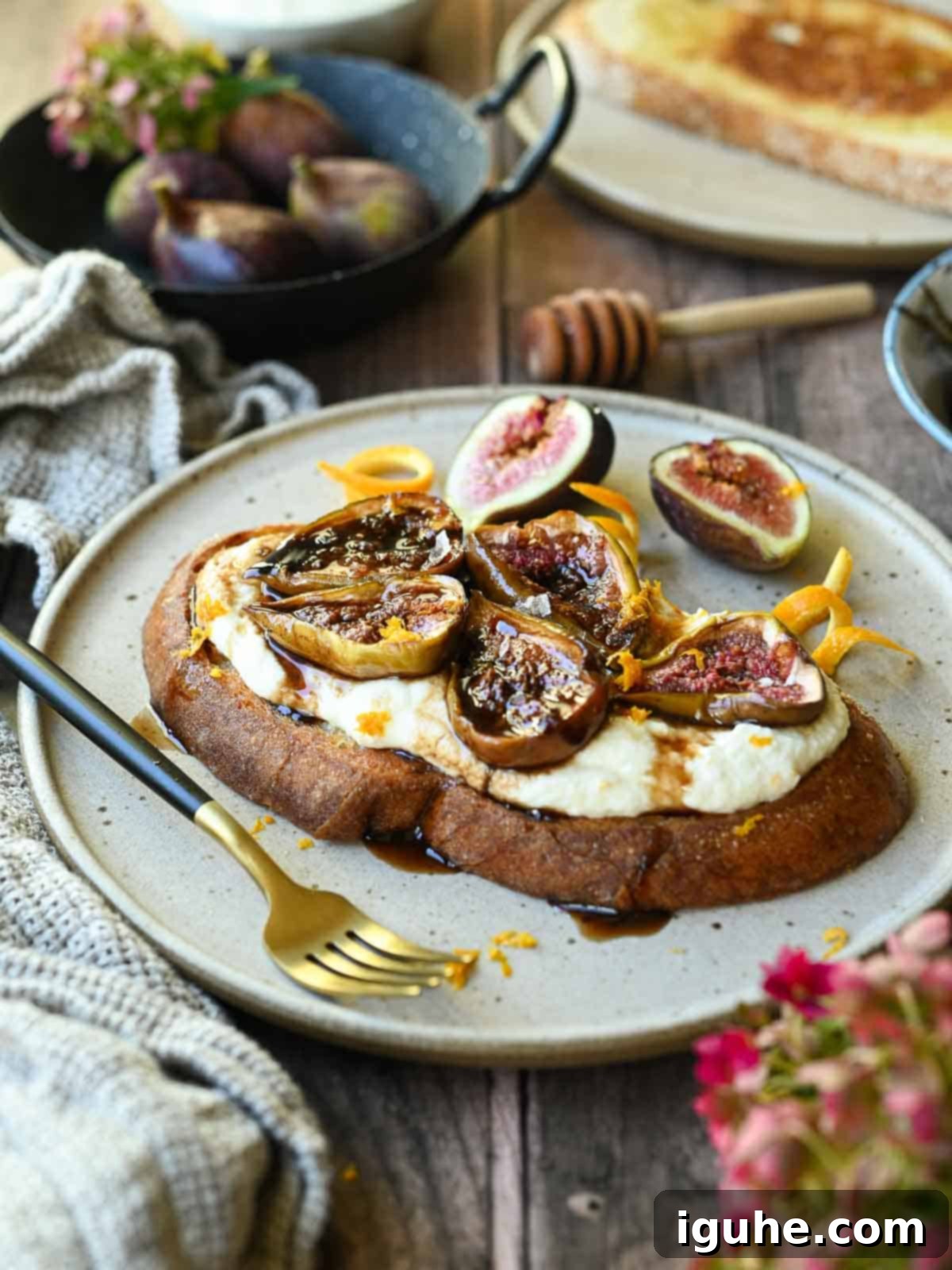 Sweet and Savory Balsamic Fig Toast 7 Finished balsamic roasted fig toast on a beige plate, adorned with orange zest, fresh figs, and a drizzle of roasting liquid.