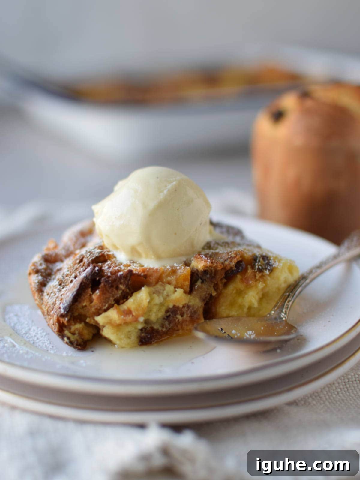 Eye-level view of bread pudding with ice cream on top on a white plate.