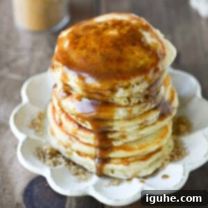 Decadent Brown Sugar Stacks 11 Close-up of fluffy brown sugar pancakes on a beige plate, generously drizzled with rich brown sugar syrup.