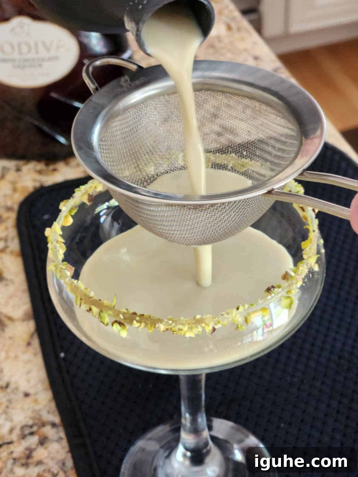 Velvet White Chocolate Pistachio Martini 5 Pistachio martini being strained into a glass.