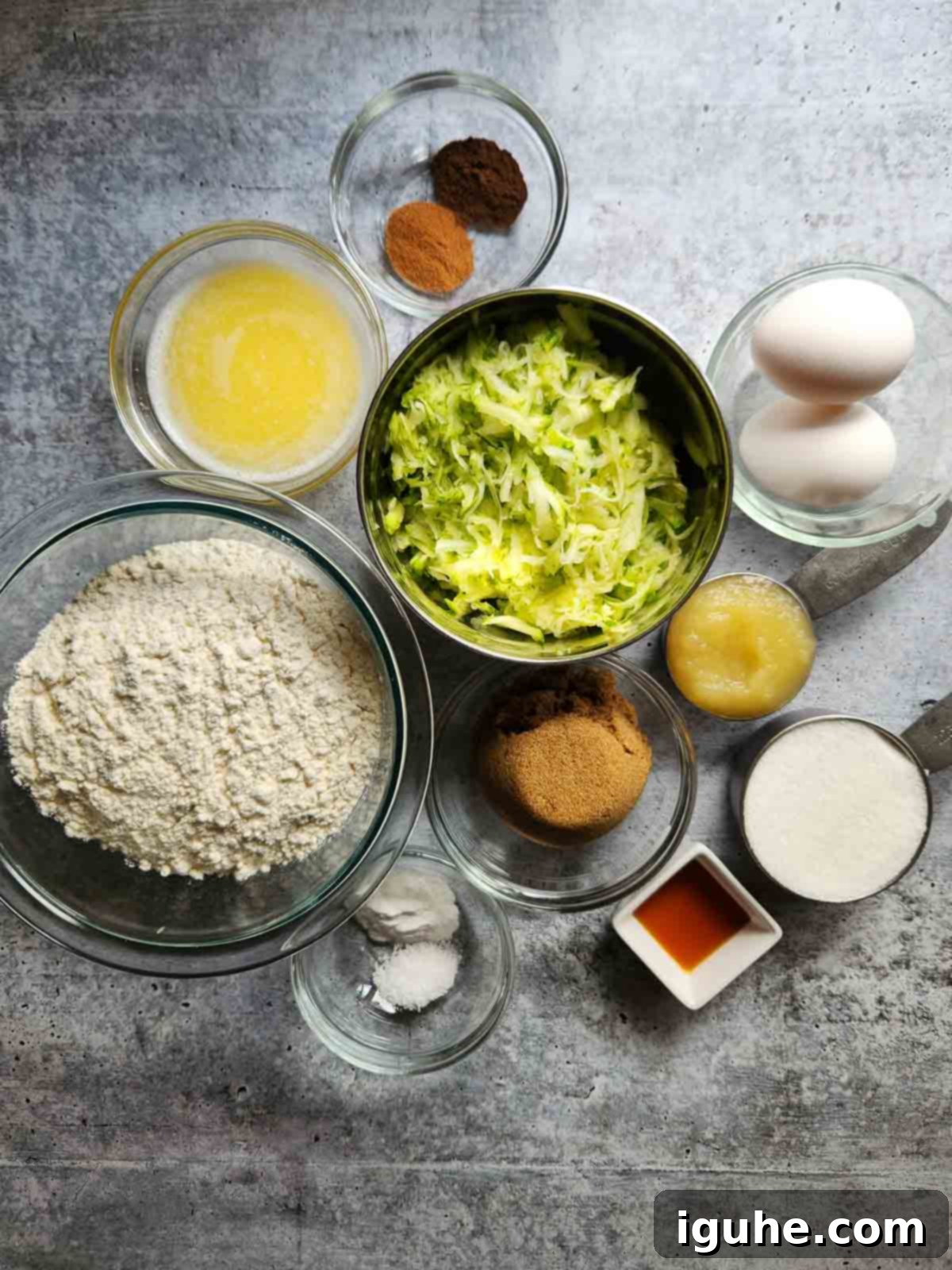 Apple-Kissed Zucchini Muffins 3 Ingredients for zucchini muffins on a concrete surface.