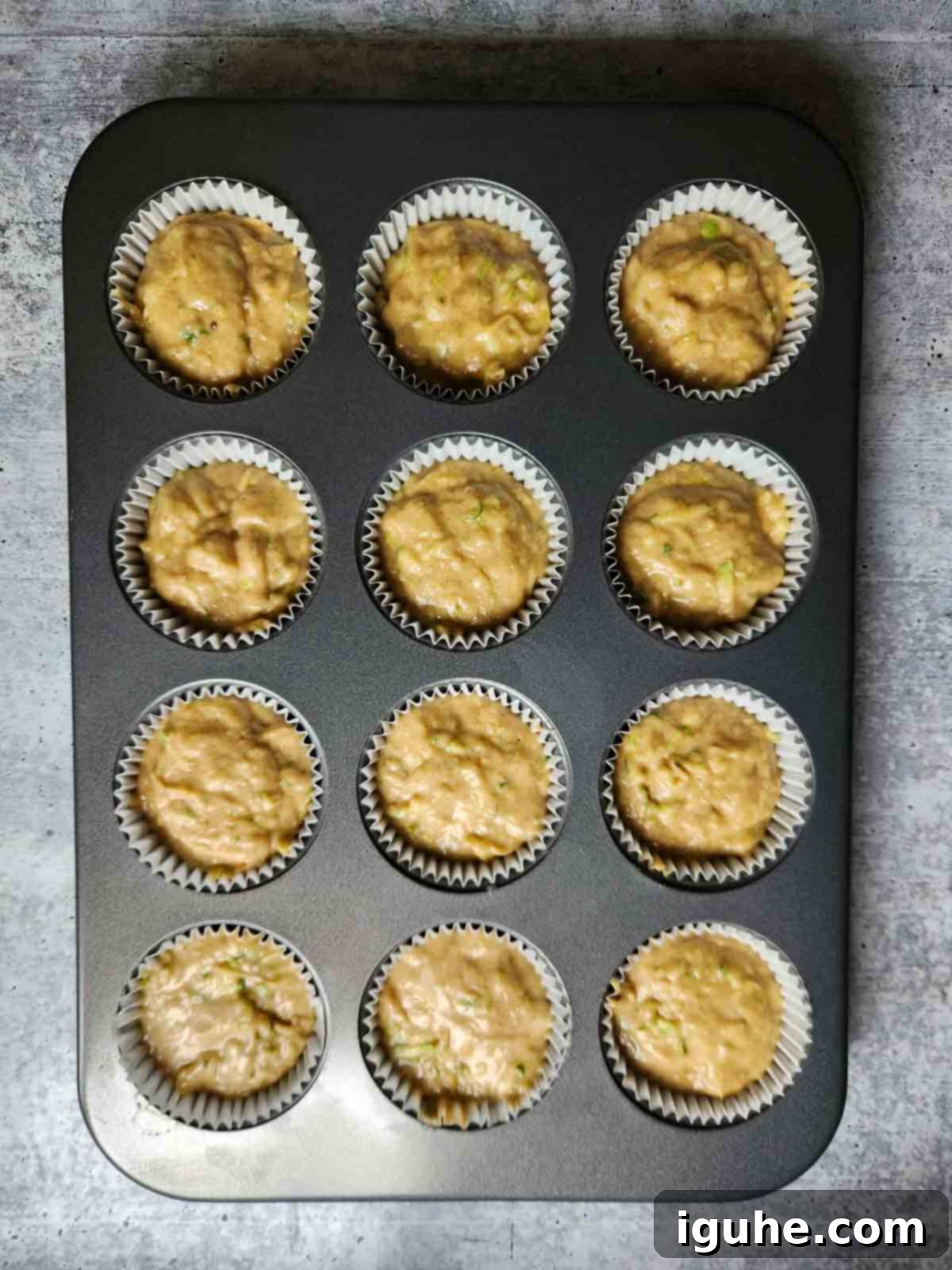 Apple-Kissed Zucchini Muffins 9 Muffin batter in a 12 cup metal muffin tin.