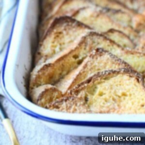 Decadent Baked Brioche French Toast 10 Close-up of baked brioche French toast casserole in a white pan, golden brown.