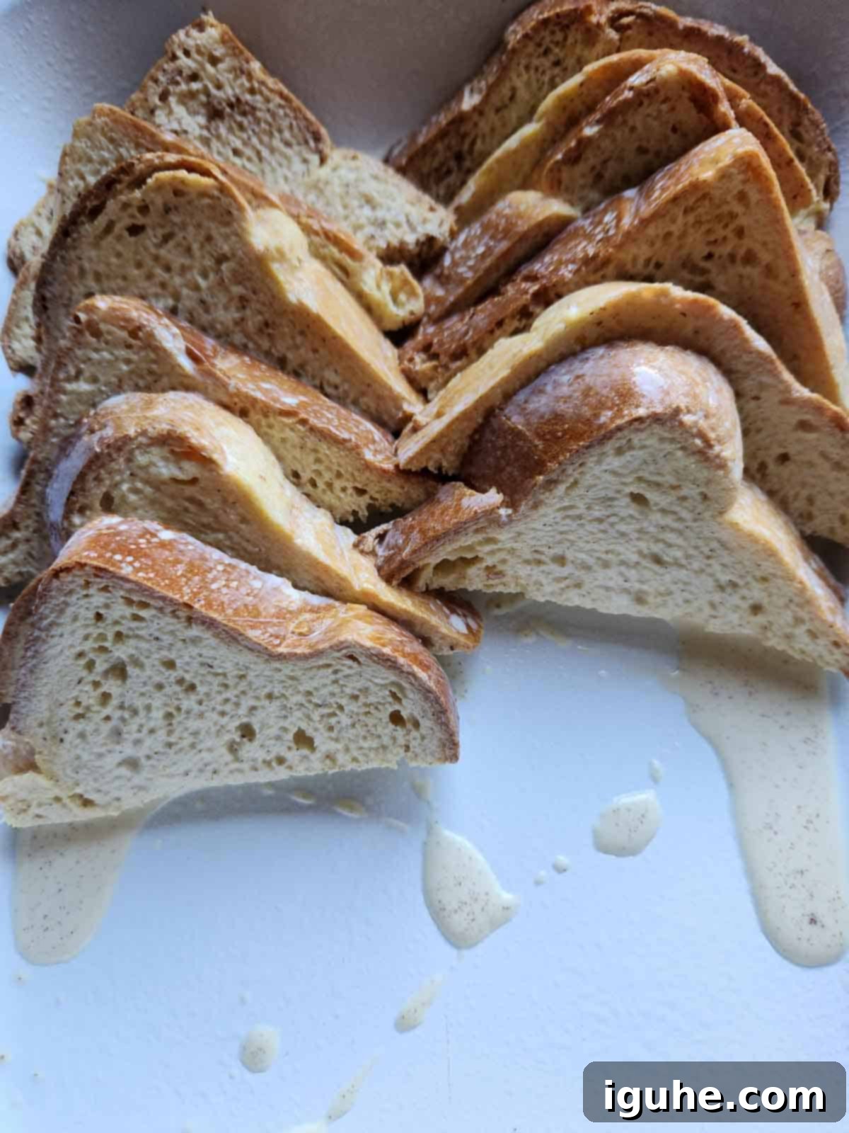 Decadent Baked Brioche French Toast 6 French toast casserole bread slices arranged in a white pan.