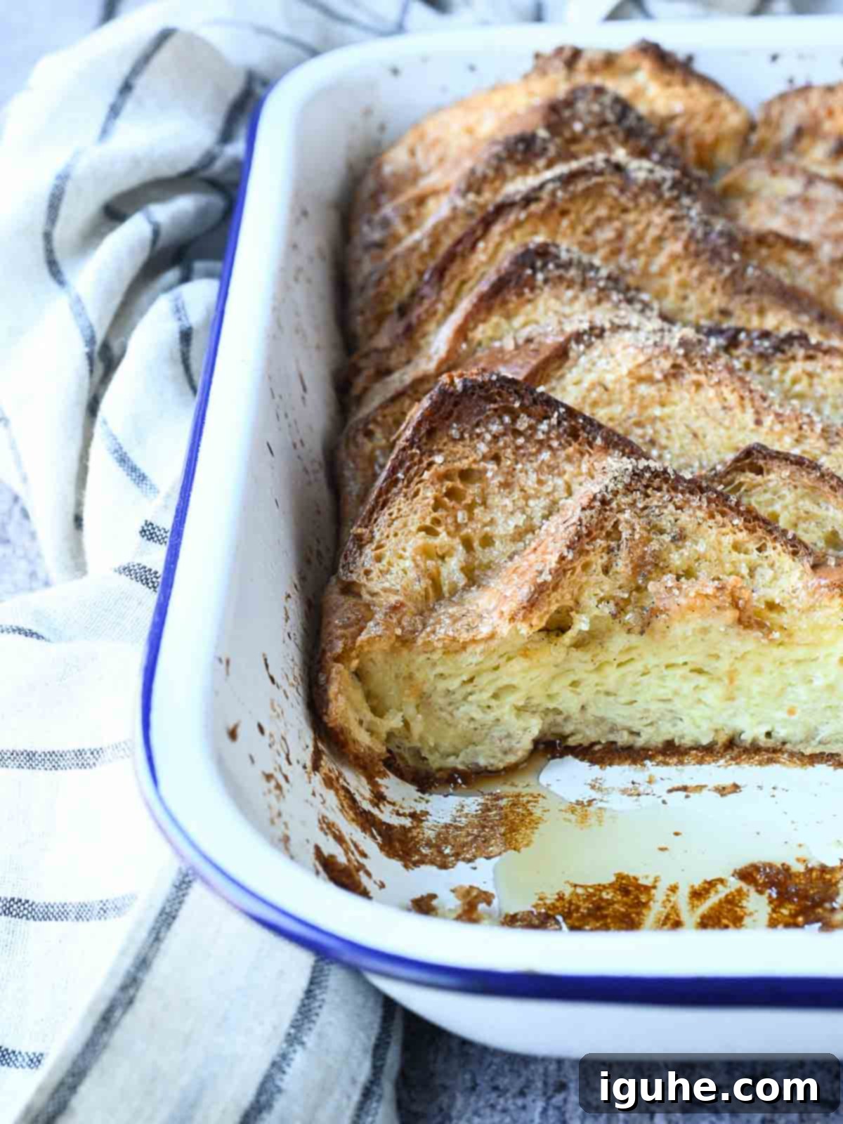 Decadent Baked Brioche French Toast 8 Baked French toast in a white pan, with a piece taken out, showing the custardy interior.