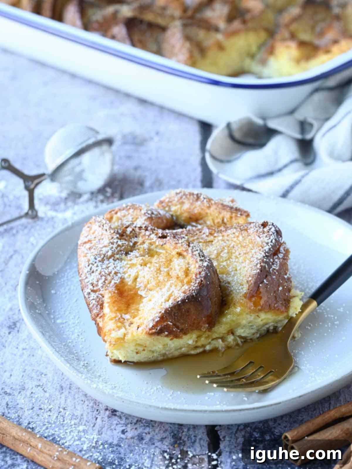 Decadent Baked Brioche French Toast 9 A perfectly golden slice of baked Brioche French toast on a white plate, ready to be enjoyed.
