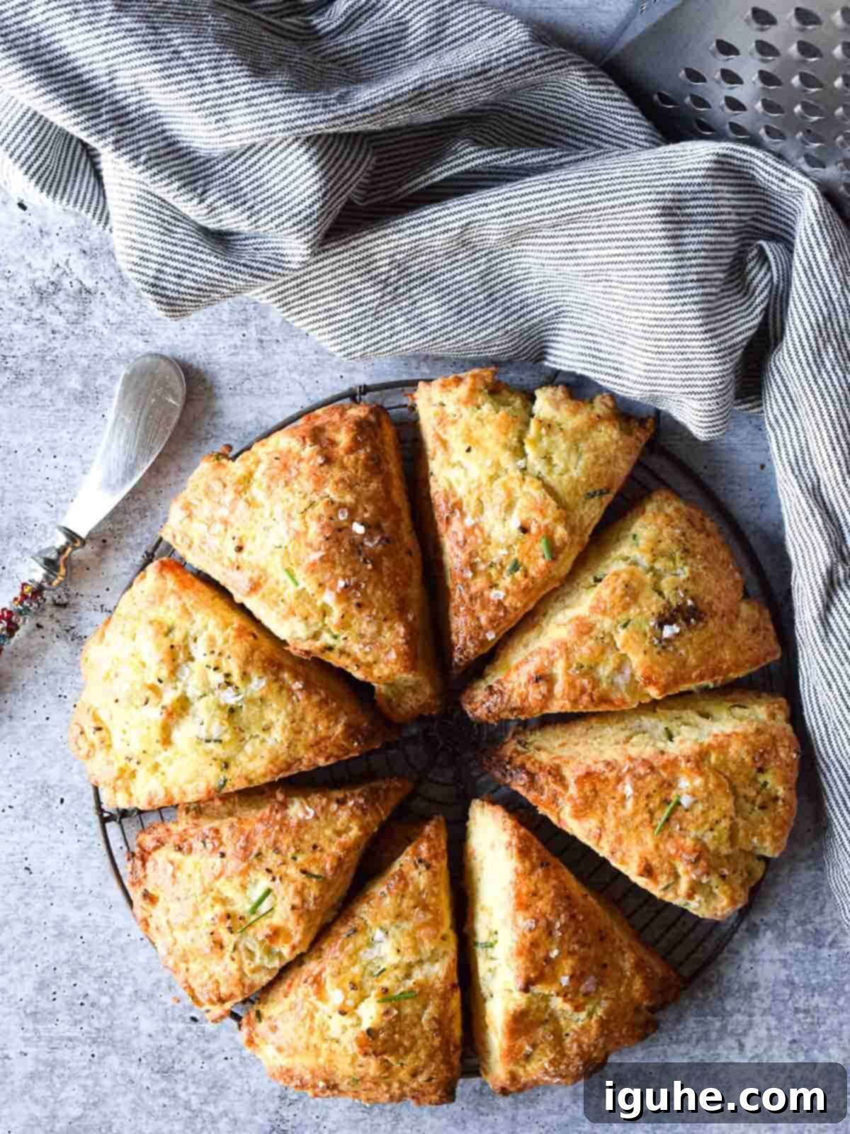 Overhead view of smoked gouda and chive scones cut in eight triangles on a concrete gray background.
