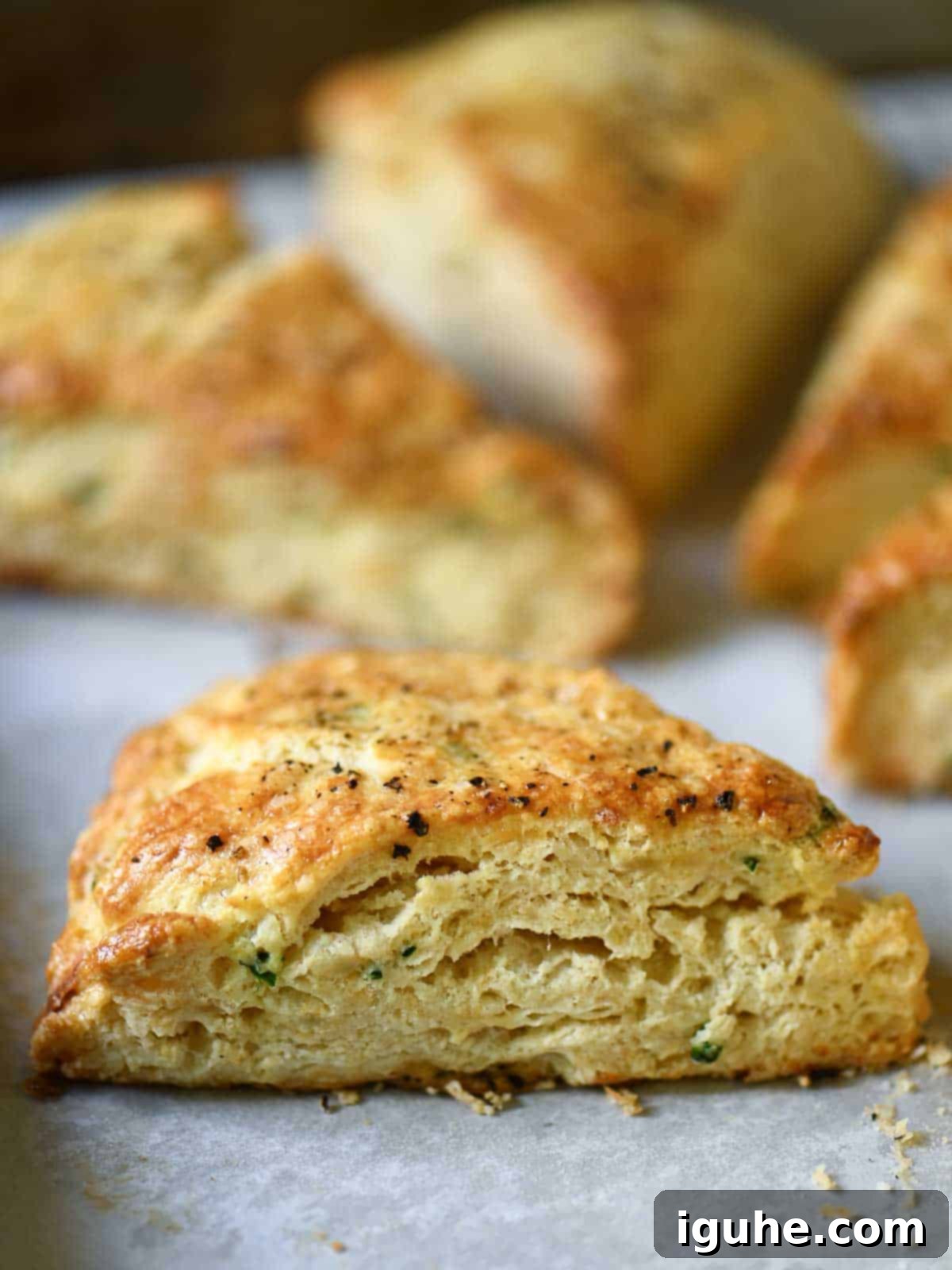 Savory Smoked Gouda and Chive Scones 8 Close-up of a savory scone from the side on parchment paper.