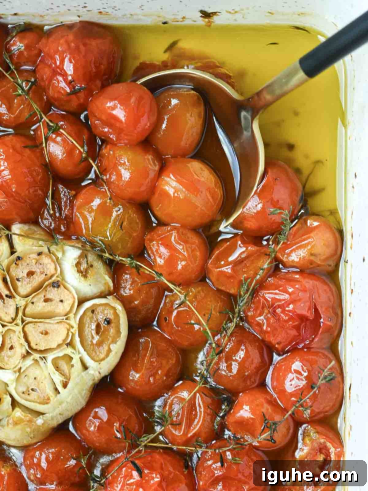 Tomato confit in a baking dish with oil and garlic.