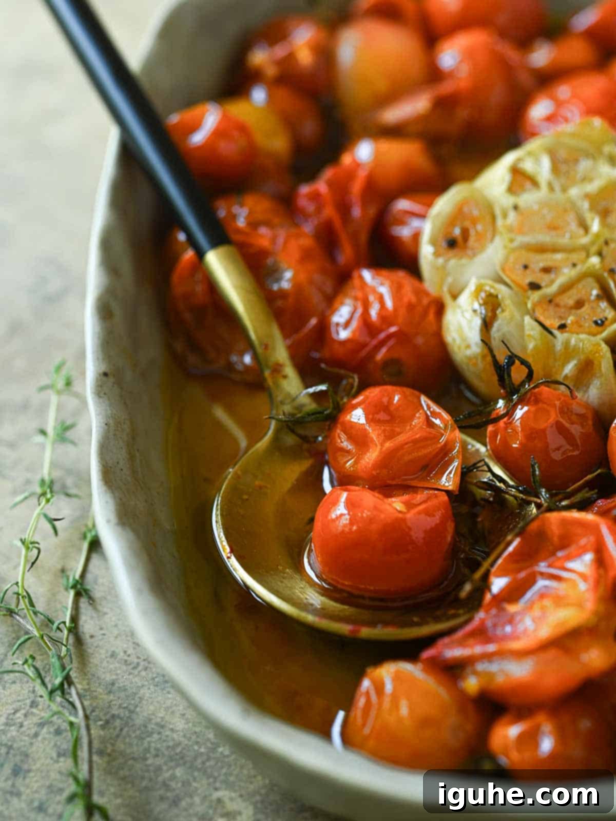 Cherry Tomato Confit with Garlic and Thyme 6 Tomato confit in a bowl with a spoon and thyme on the side.