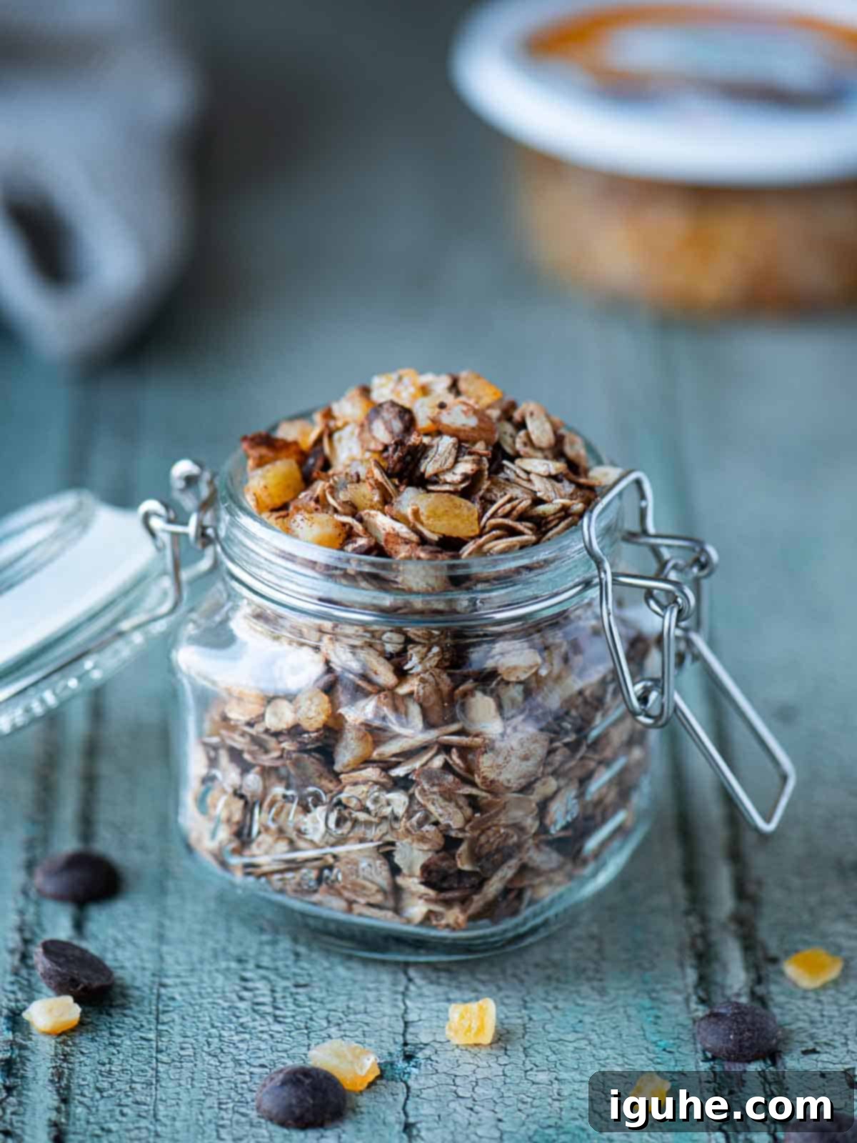 Chocolate muesli in a clear mason jar on a blue surface, showcasing the vibrant candied orange and rich chocolate.