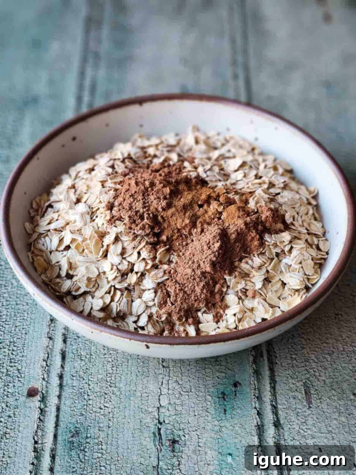 Candied Orange Chocolate Muesli 4 Oats, chia seeds, cocoa powder, and cinnamon mixed together in a beige bowl, ready for toasting.
