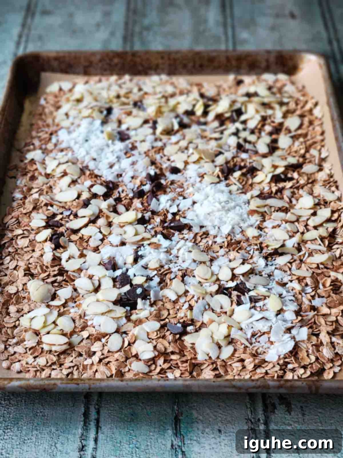 Candied Orange Chocolate Muesli 6 The muesli mixture on a baking sheet after the second bake, showing toasted oats, coconut flakes, and melting chocolate.
