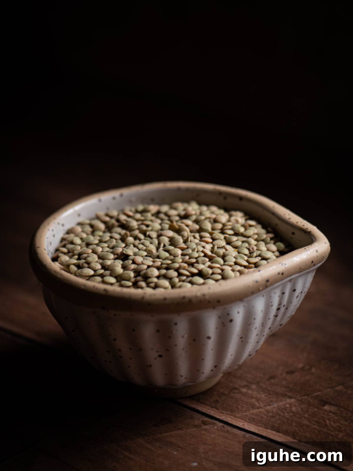 Hearty Bacon and Lentil Soup 3 Dry green lentils in a beige bowl, highlighting the main ingredient for the soup.