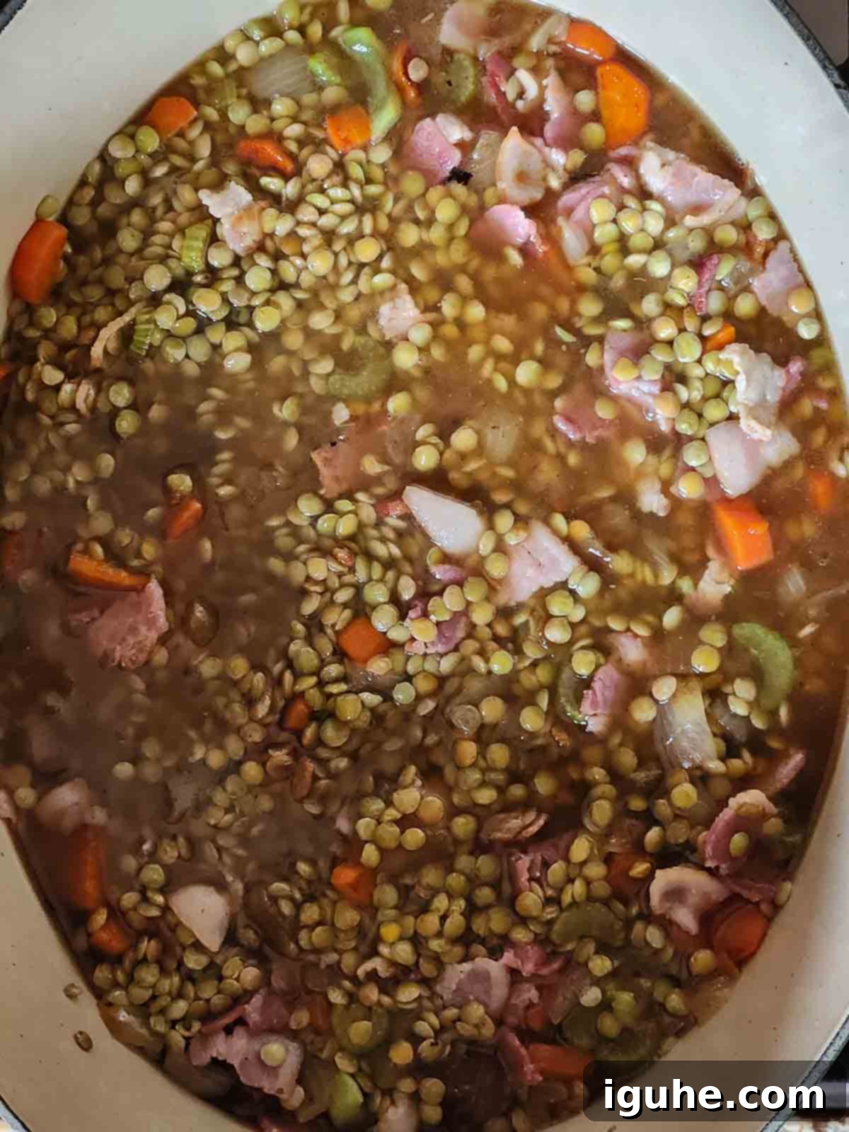 Hearty Bacon Lentil Soup 6 Dry brown lentils added to the sautéed mirepoix in a pot, with bacon and stock added, ready to simmer and absorb flavors.