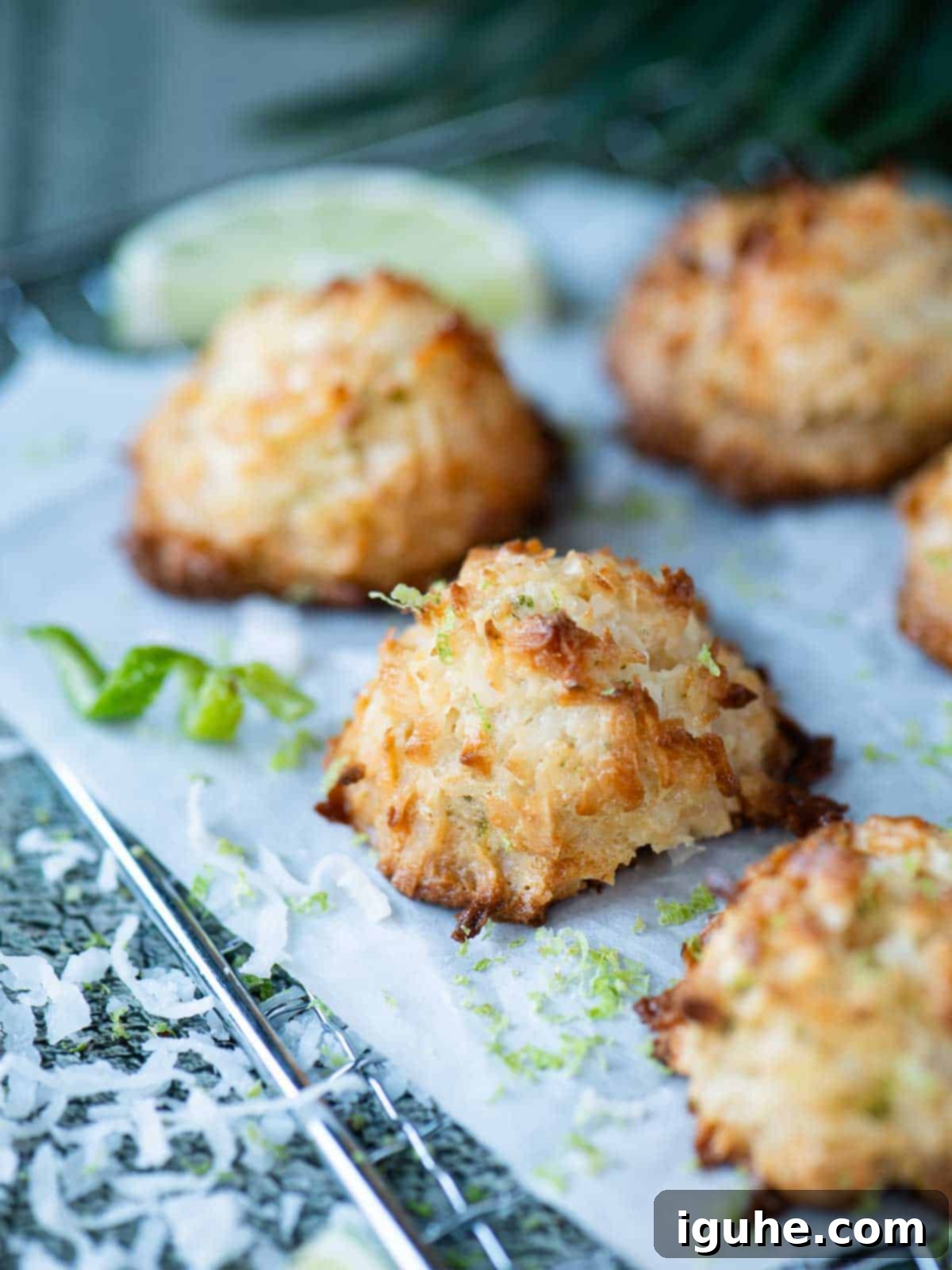 Coconut macaroons on a wire rack with lime zest and coconut around it, evoking a tropical summer vibe.