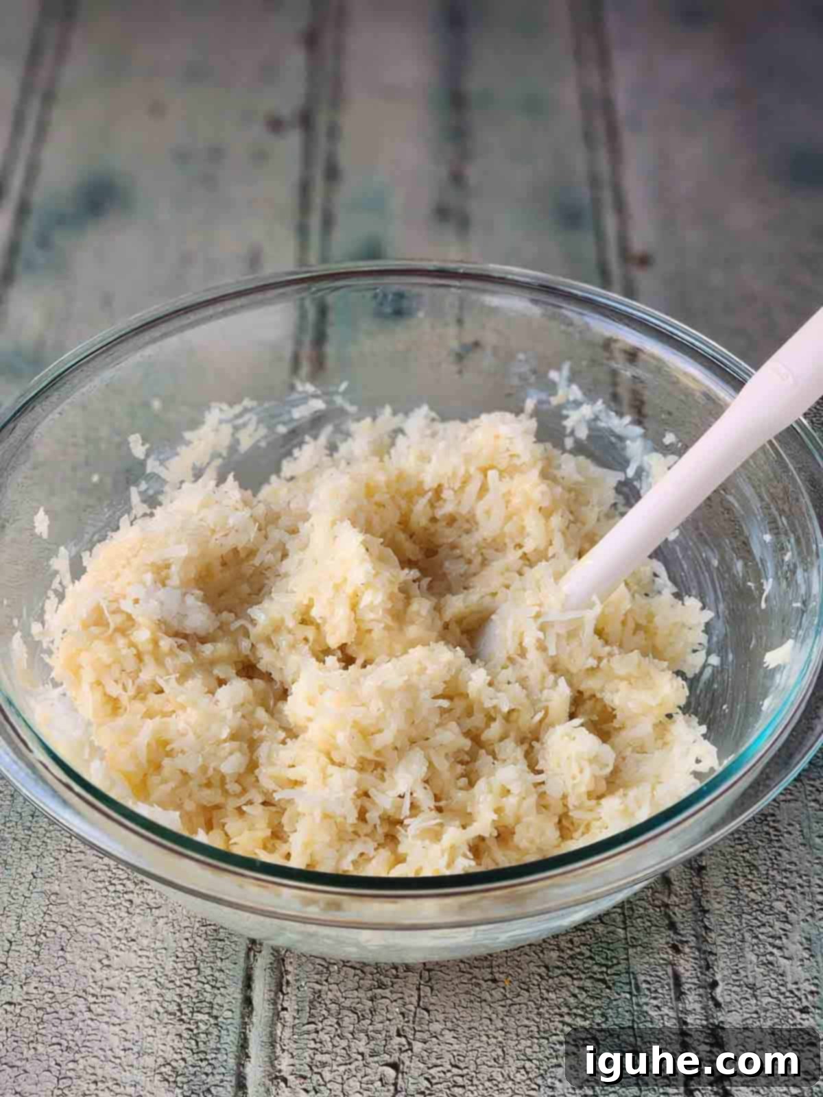 Tropical Coconut Lime Macaroons 5 Mixed ingredients for coconut macaroons in a clear bowl, showing a cohesive texture.