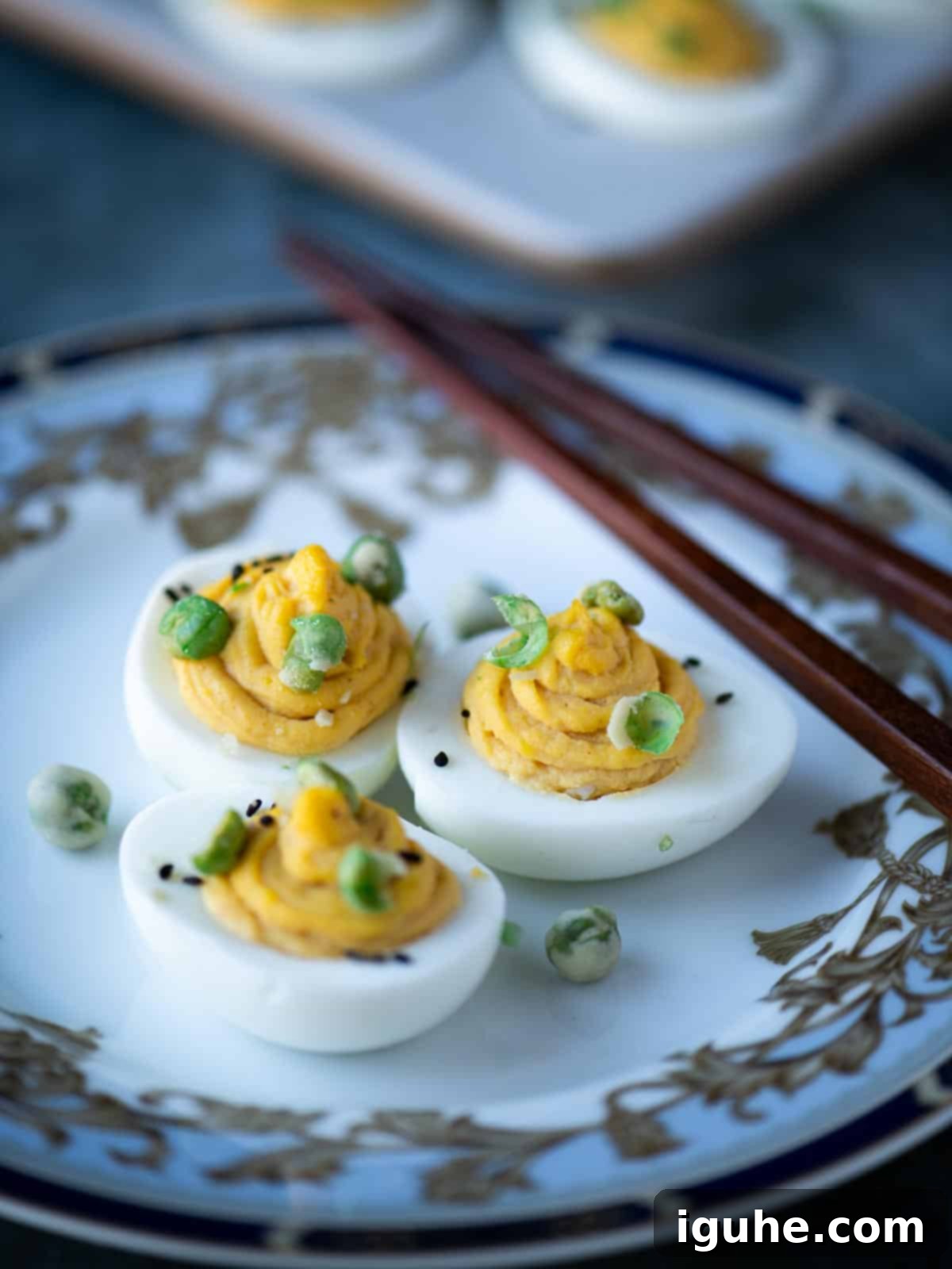 Umami Deviled Eggs 11 Three deviled eggs on a pretty plate with chopsticks.
