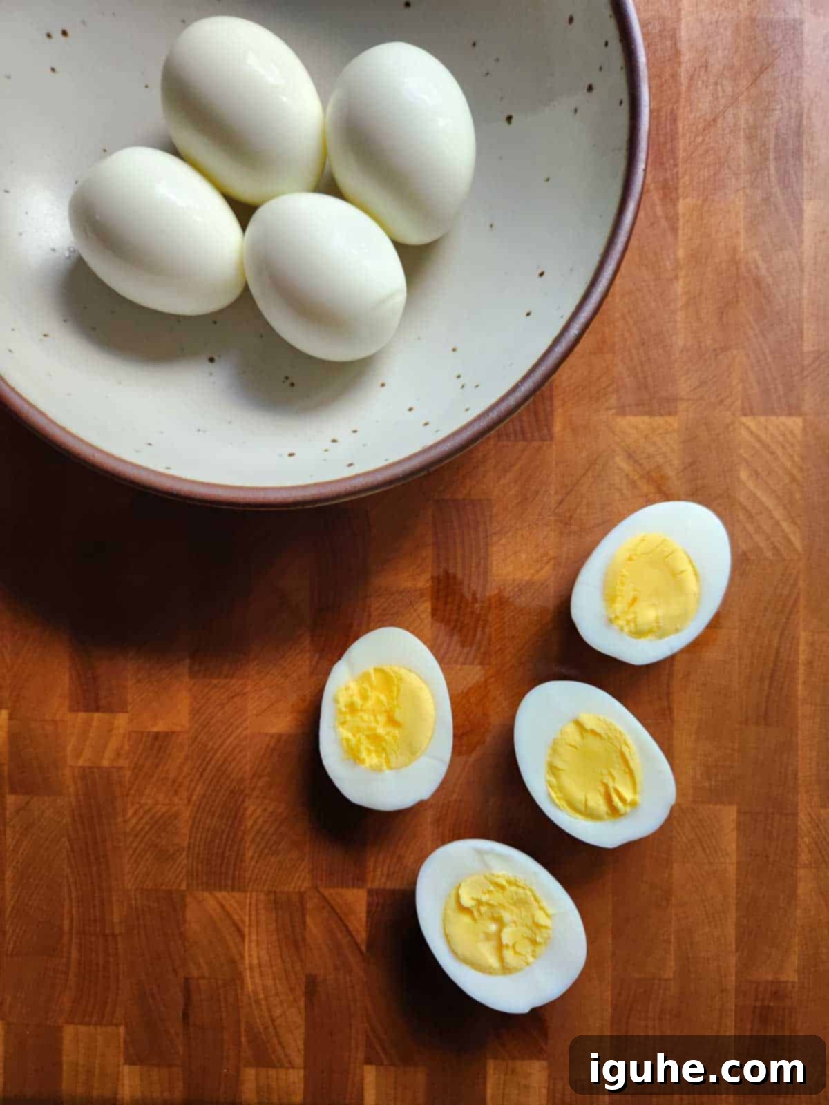 Umami Deviled Eggs 5 Hard boiled eggs sliced open on a wood cutting board.