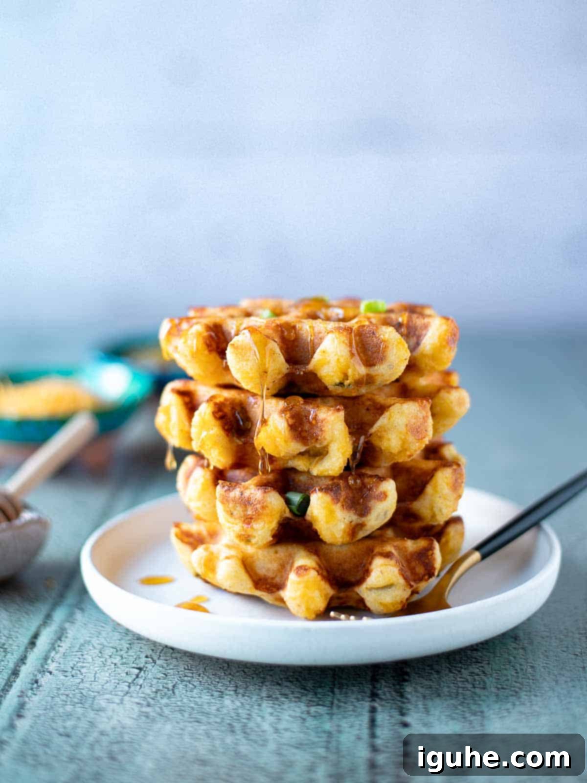 Zesty Cheddar Chili Waffles 2 Stack of savory waffles on a white plate with a fork to the right.